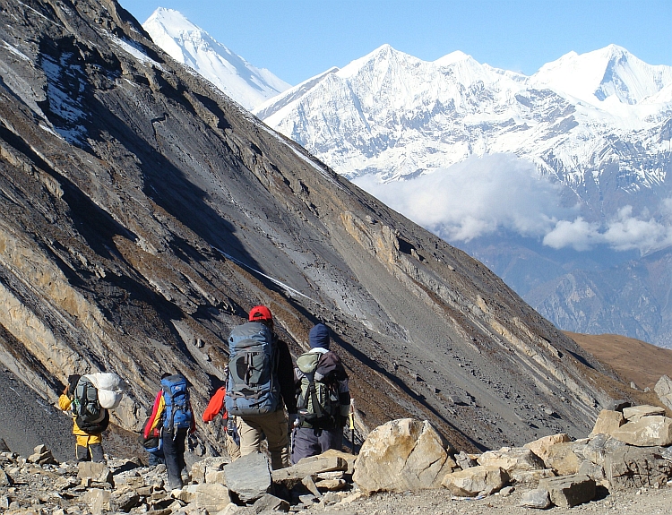 Het Shithead Team en een drager op de afdaling naar Muktinath. De grote witte bergtop links is de Dhaulagiri (8.167 m)